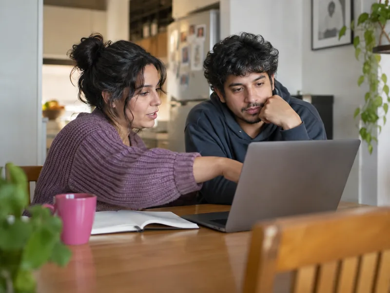 Dos personas frente a un notebook con un cuaderno abierto